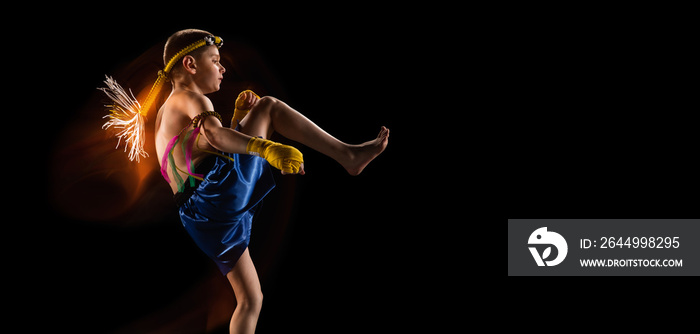 Little boy exercising thai boxing on black background. Fighter practicing, training in martial arts in action, motion. Evolution of movement, catching moment.