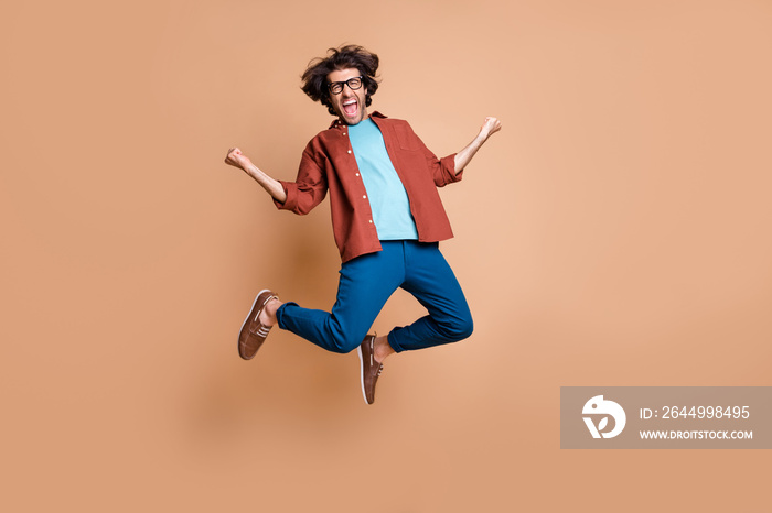 Full length photo portrait of wild guy celebrating jumping up isolated on pastel beige colored background