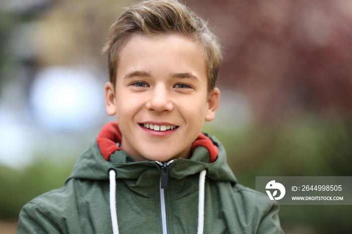 Portrait of cheerful teenager outdoors on blurred background, closeup