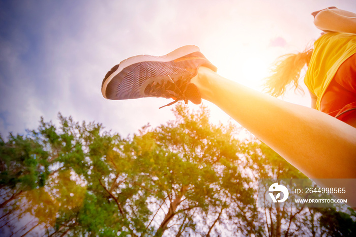 Closeup of athlete’s feet running at the park. Fitness woman jogging outdoors. Exercising on forest path. Healthy, fitness, wellness lifestyle. Sport, cardio, workout concept