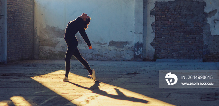 Ballerina dancing in a dusty abandoned building on a sunny day