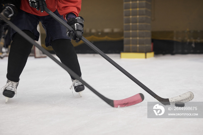 Low section portrait of unrecognizable hockey player leading pluck on ice, copy space