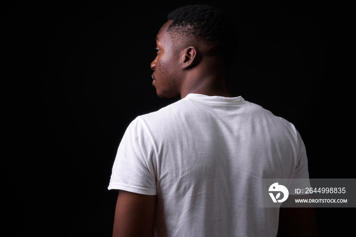 Young handsome African man against black background