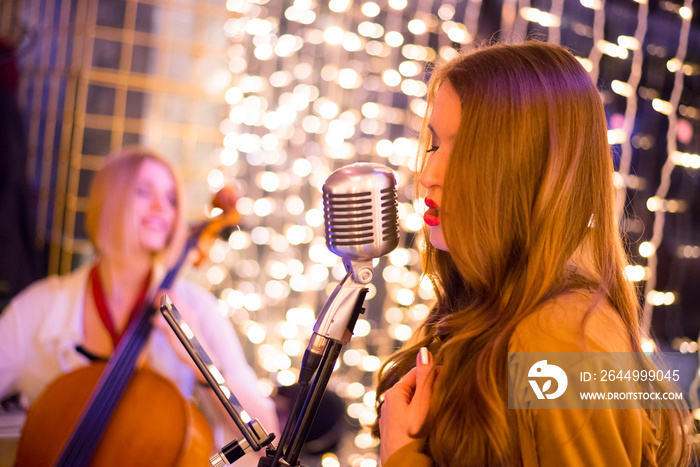 Female singer singing on the concert with her band on the restaurant stage at night