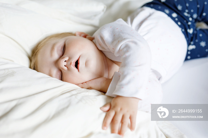 Cute adorable baby girl of 6 months sleeping peaceful in bed