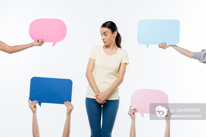 What is this. Nice surprised young woman standing against white background and looking at the sign while being curious what is this