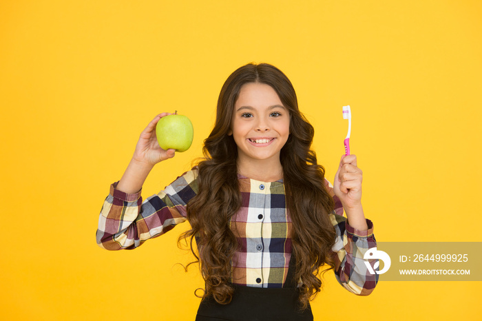 Beautiful natural smile. Happy child hold green apple and toothbrush. Little girl smile with brush and natural fruit. Natural dental care. Gentle natural way to white teeth