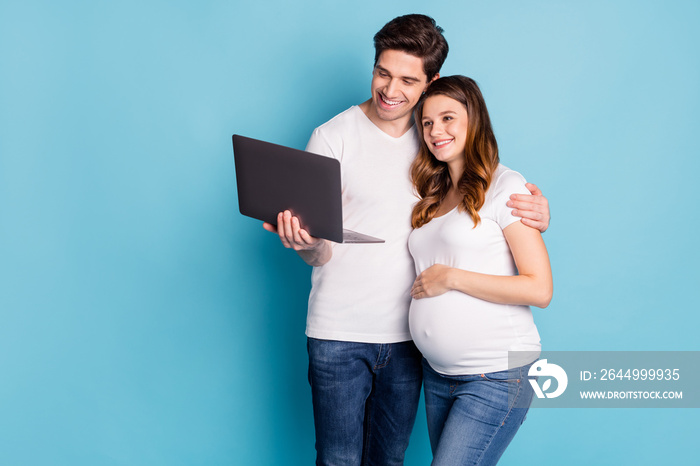 Photo of optimistic pregnant couple watch laptop wear white t-shirts isolated on cyan color background