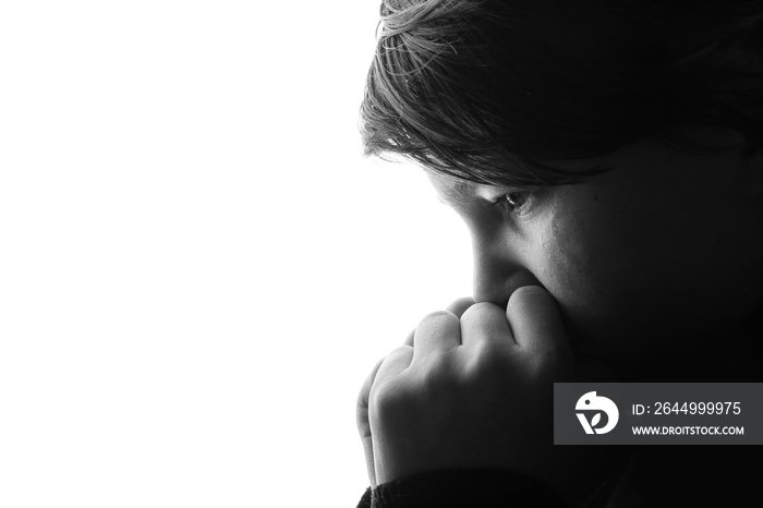 Black and white portrait of young sad boy crying with sad eyes. White background. Free space for text. Tear on cheek of unhappy teenager.