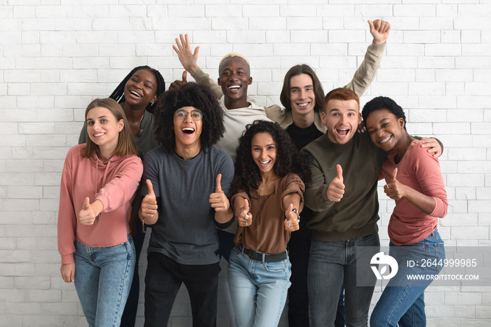 Beautiful multiethnic young people posing over white brick wall