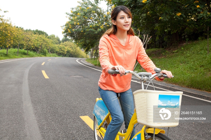 一个年轻女大学生在校园里骑车