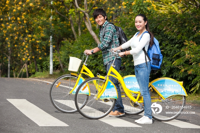 年轻大学生情侣在校园里骑车过马路