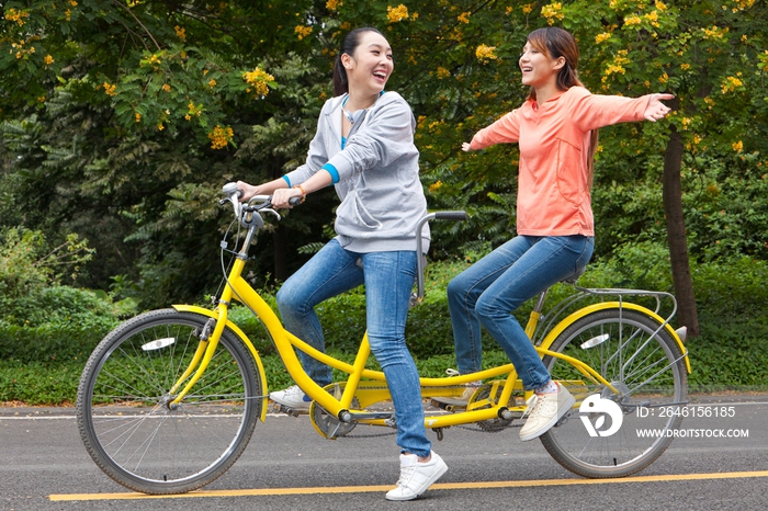 两个年轻女大学生在校园里骑车