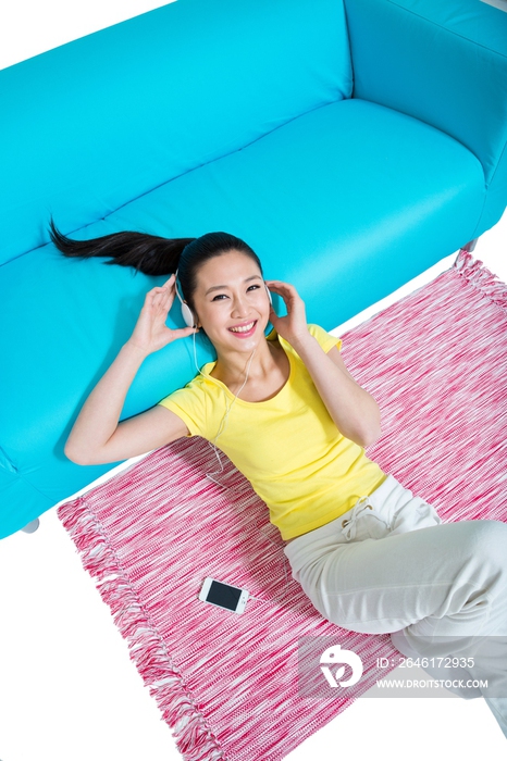 棚拍年轻女人躺在地毯上听音乐