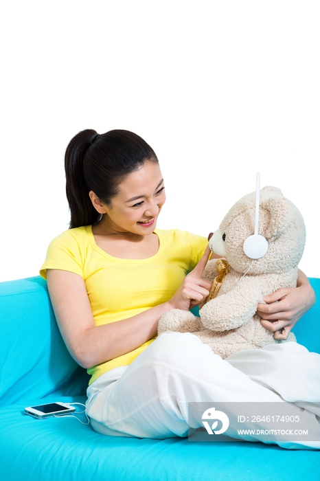 棚拍年轻女人坐在沙发上玩玩具熊