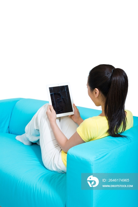 棚拍年轻女人坐在沙发上玩平板电脑