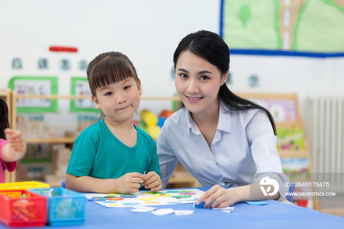 幼儿园女老师辅导儿童做手工