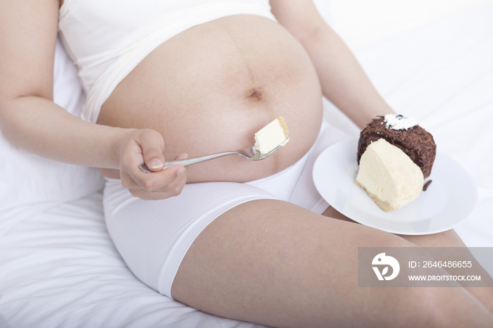 孕妇坐在床上吃蛋糕