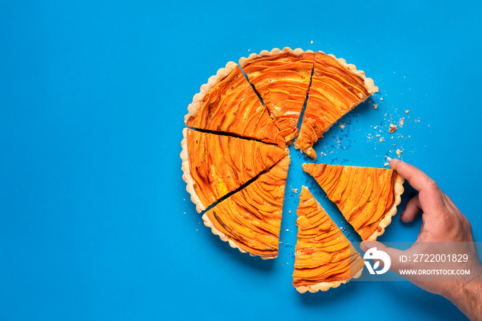 Man hand taking a slice of sweet potato tart