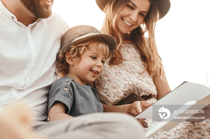 Happy parents and son reading book together