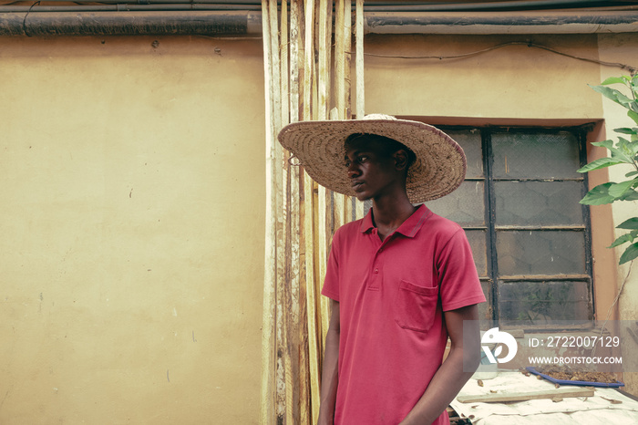 Nigerian boy with a straw hat at their family backyard