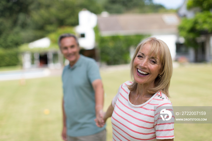 Portrait happy senior couple holding hands in backyard