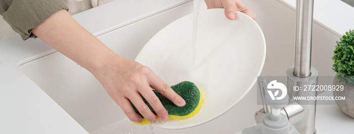 Woman housewife is doing the dishes at home kitchen.