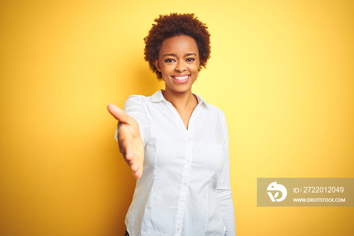 非裔美国商业女性，在孤立的黄色背景下微笑友好地握手