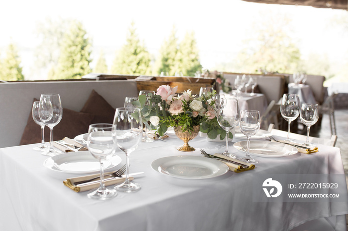 Wedding table setting decorated with fresh flowers in a brass vase. Wedding floristry. Banquet table