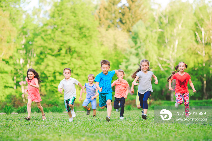许多不同的孩子，男孩和女孩在阳光明媚的夏天穿着休闲服在公园里跑步