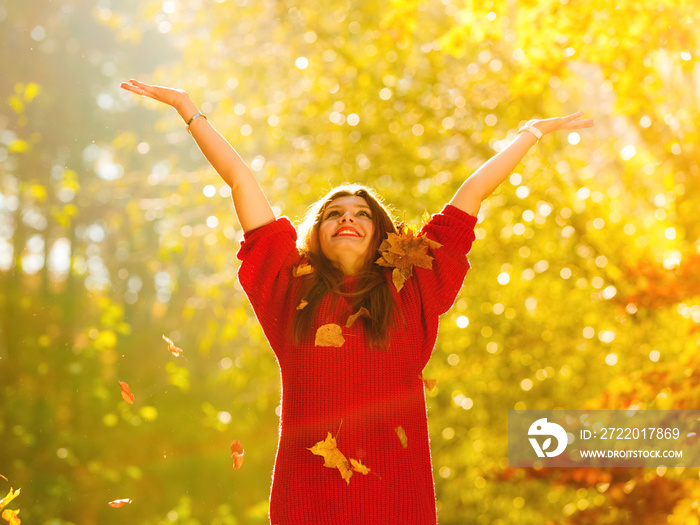 woman relaxing in autumn park throwing leaves up in the air