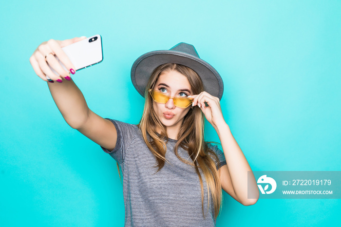 Young cheerful attractive taking selfie on the camera of her phone, wearing casual summer outfit and