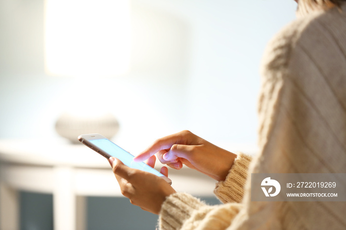 Woman using mobile phone in evening, closeup