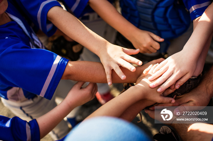 Baseball players stacking hands in huddle