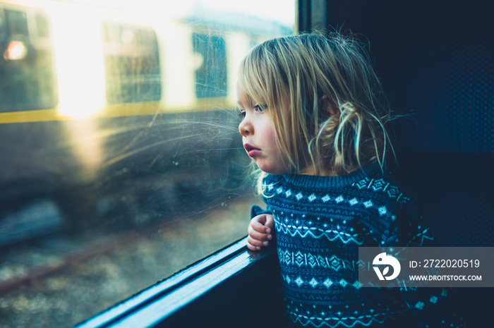 Little toddler on a train looking out the window