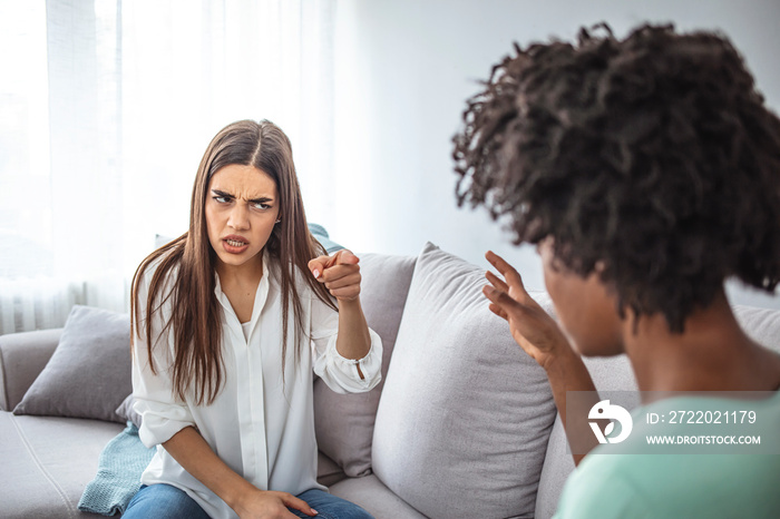 Two friends not talking to each other after fight on the sofa in sitting room at home. Two upset fri