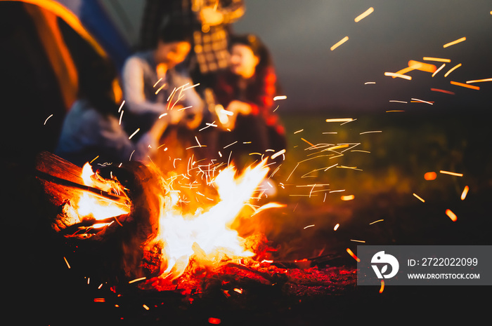 夏天，森林里露营帐篷附近，游客坐在明亮的篝火旁，点燃篝火