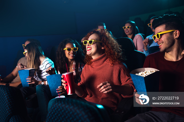 Group of cheerful people laughing while watching movie in cinema with 3D glasses.