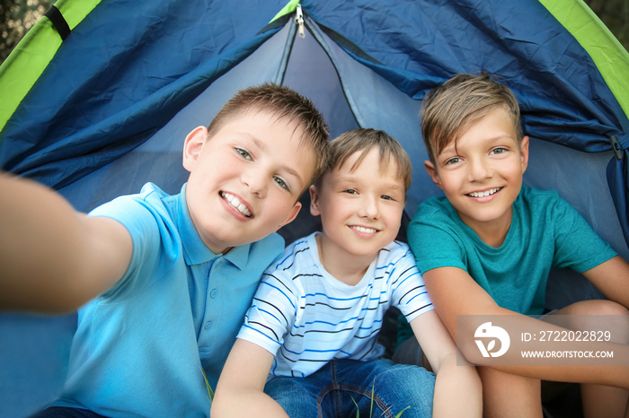 Children taking selfie near tent at summer camp