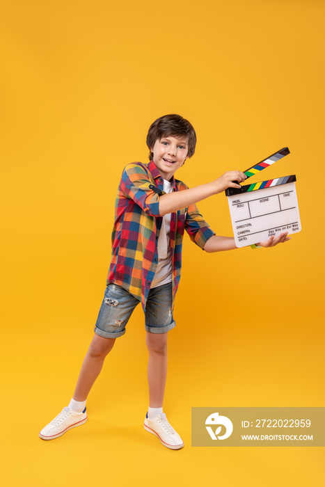 Future producer. Cheerful dark-haired boy smiling and holding a table