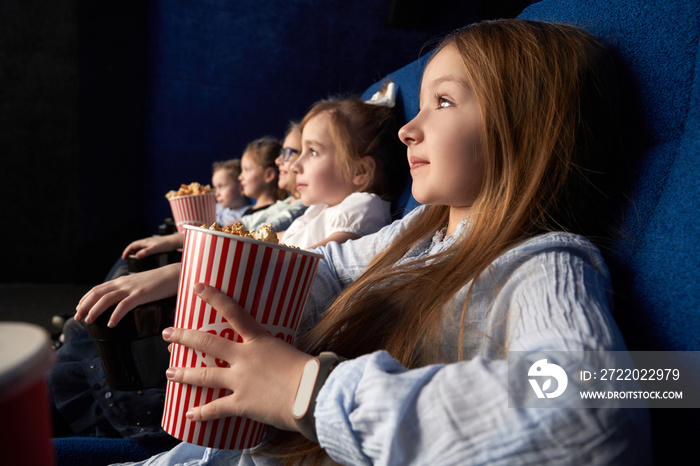 Little girl with friends sitting in cinema.