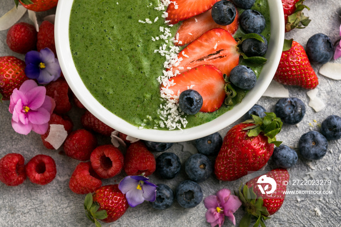 Matcha green tea breakfast superfoods smoothies bowl topped with strawberries, blueberries, coconut 