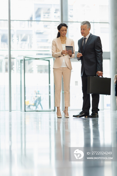 Business people using digital tablet in office lobby