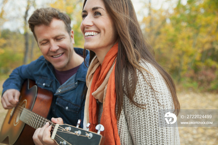 Man playing guitar for woman at park