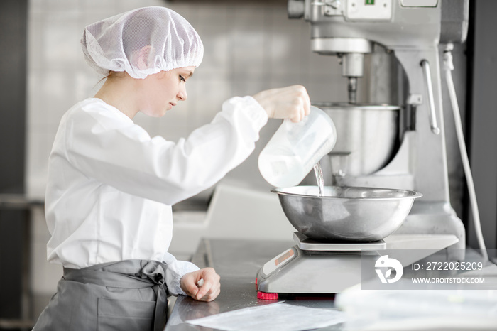 在面包制造厂工作的糕点配料均匀的女性糖果师
