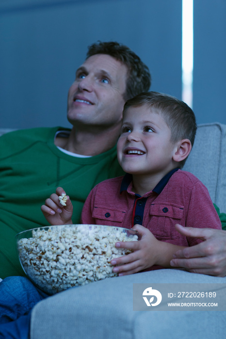 快乐的父子在沙发上看电影吃爆米花