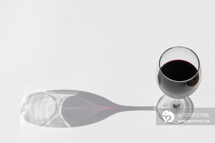 一杯红葡萄酒，背景为白色，阴影较深。
