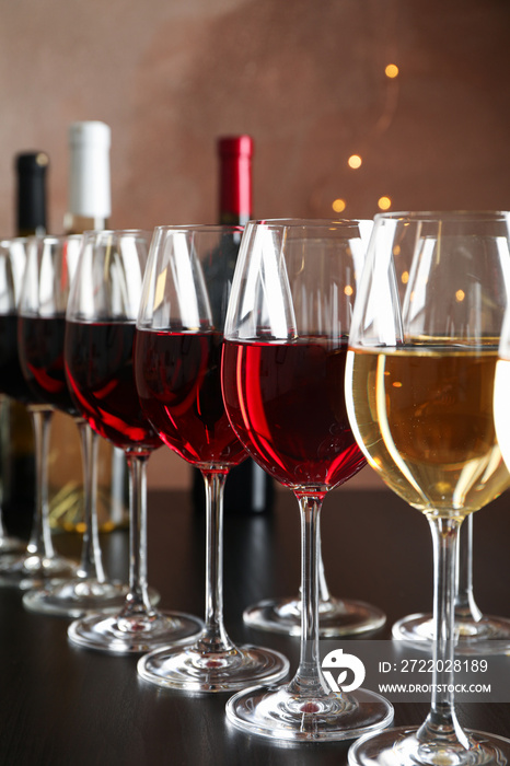 Bottles and glasses with wine on dark table, blurred lights, closeup