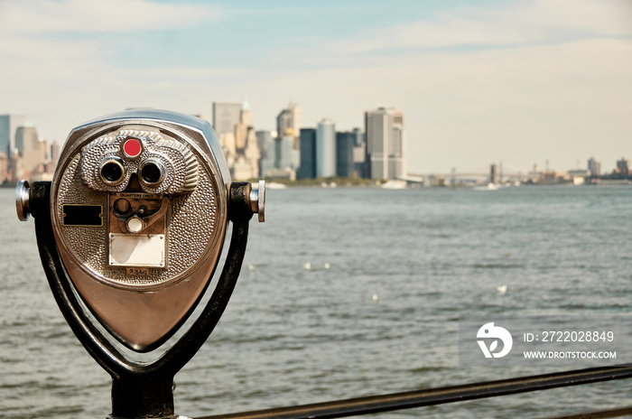 Manhattan skyline and New York Harbor seen from a distance on Liberty Island. Tower viewer binocular