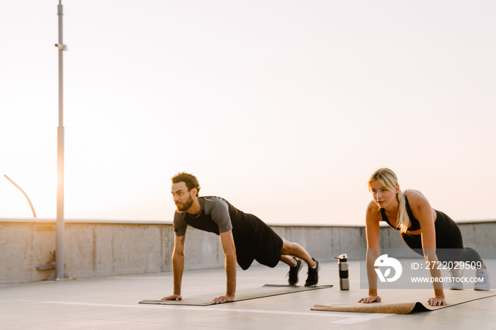 Young man and woman doing exercise while working out together on parking